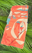 Colorful towel with abstract designs by artist Nick Kuchar on a green leaf background