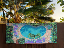 full size view of poolside design towel (by artist Christie Shinn) hanging on a fence with fan palms in the background. 