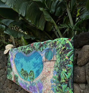 side view of Poolside towel design hanging on a lava wall with banana leaves in the background.